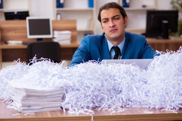 Joven empleado masculino y muchos papeles cortados en la oficina — Foto de Stock