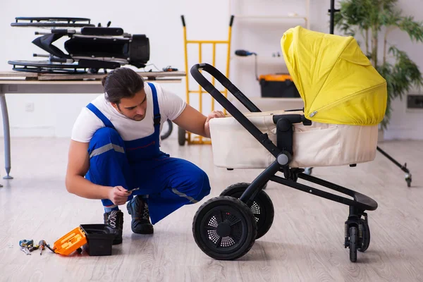 Giovane riparatore di sesso maschile riparazione perambulatore all'interno — Foto Stock