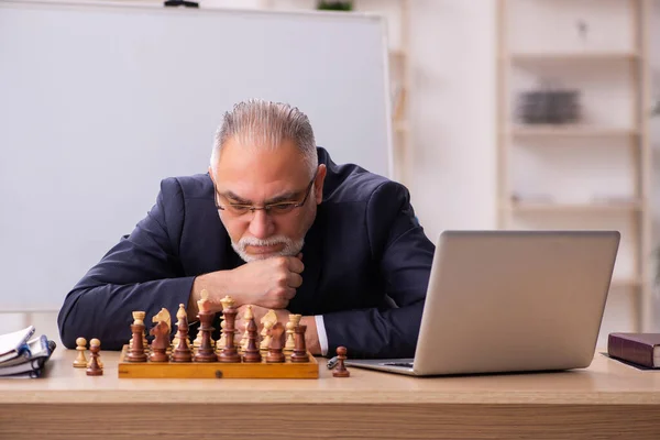 Viejo empleado jugando ajedrez en el lugar de trabajo — Foto de Stock