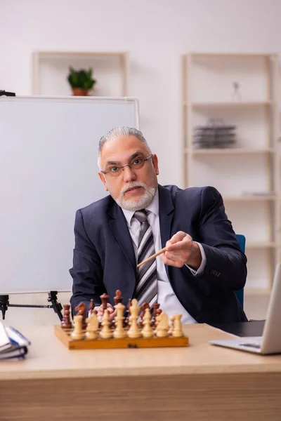 Old male employee playing chess at workplace — Stock Photo, Image