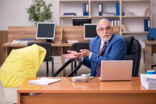 Betagter Geschäftsmann kümmert sich um Neugeborenes am Arbeitsplatz — Stockfoto