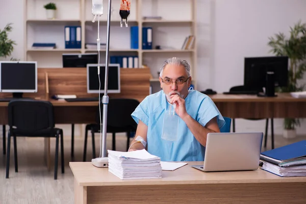 Oude mannelijke werknemer in het concept bloedtransfusie — Stockfoto
