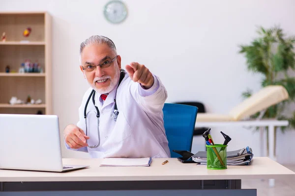 Old male doctor working in the clinic — Stock Photo, Image