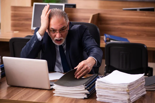 Velho empregado masculino e muito trabalho no escritório — Fotografia de Stock