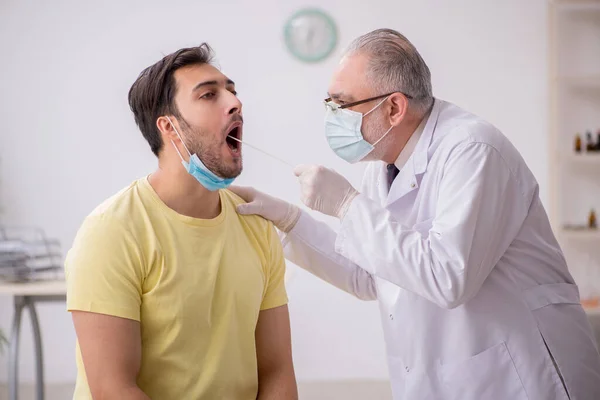 Jovem paciente do sexo masculino visitando velho médico otorrinolaringologia — Fotografia de Stock