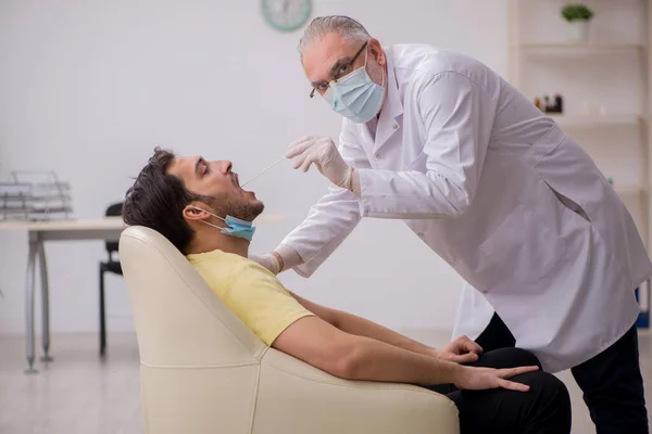 Paciente masculino joven que visita a un viejo médico otorrinolaringologis —  Fotos de Stock