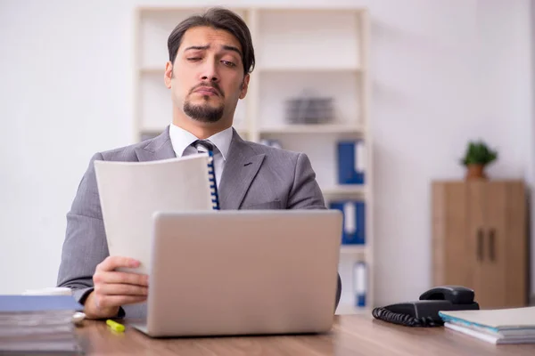 Jovem atraente masculino empregado sentado no local de trabalho — Fotografia de Stock