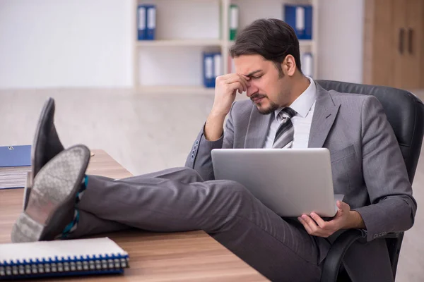 Jovem atraente masculino empregado sentado no local de trabalho — Fotografia de Stock