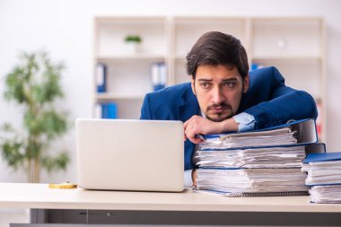 Ofisteki aşırı işten memnun olmayan genç bir erkek işçi.