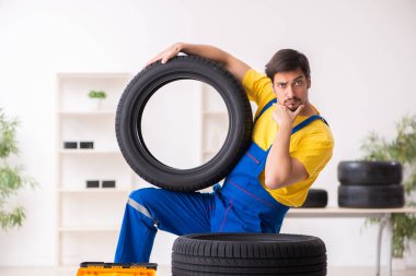 Atölyede lastiği olan genç bir erkek tamirci.