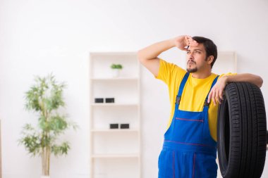 Atölyede lastiği olan genç bir erkek tamirci.