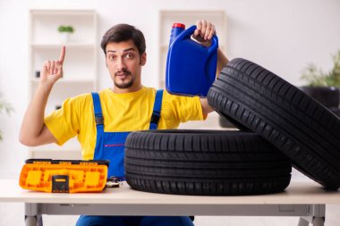 Atölyede lastiği olan genç bir erkek tamirci.