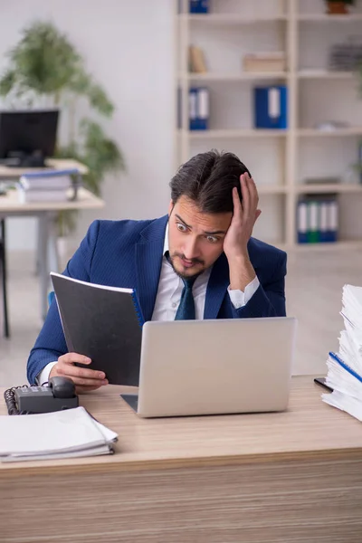 Young male employee unhappy with excessive work in the office — Stock Photo, Image