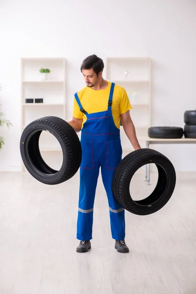 Joven trabajador de garaje con neumático en el taller —  Fotos de Stock