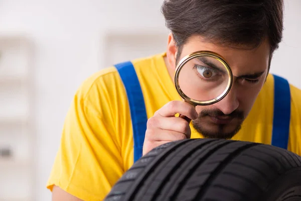 Joven trabajador de garaje con neumático en el taller — Foto de Stock