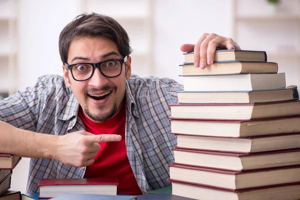 Joven estudiante masculino y demasiados libros en el aula — Foto de Stock