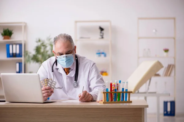 Старый врач-мужчина, работающий в клинике во время пандемии — стоковое фото