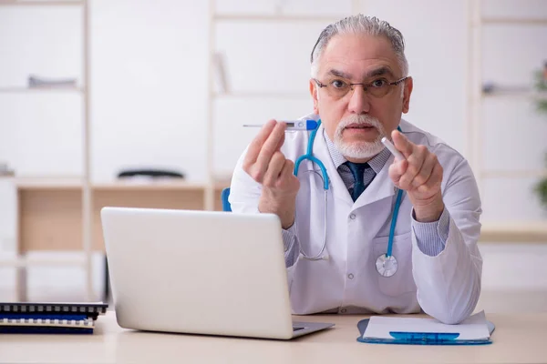 Klinikte çalışan yaşlı erkek doktor. — Stok fotoğraf