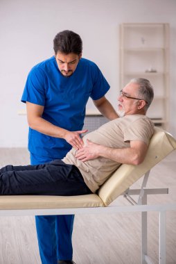 Yaşlı erkek hasta, genç doktor.