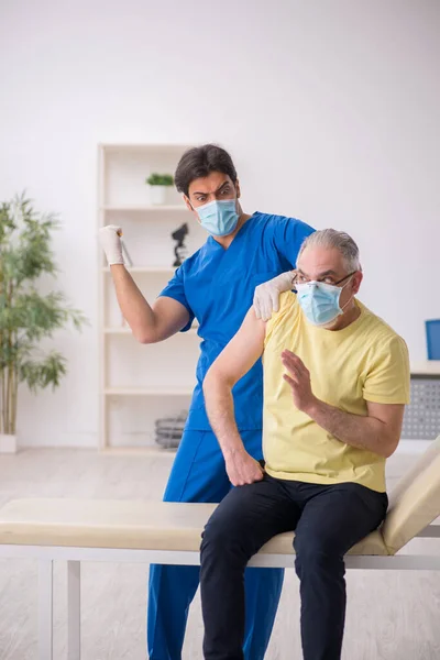 Paciente do sexo masculino velho visting jovem médico do sexo masculino na vacinação concep — Fotografia de Stock