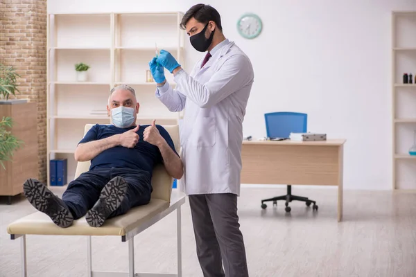 Paciente varón de edad que visita al médico varón joven en contacto con la vacunación — Foto de Stock