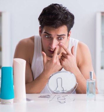 Genç yakışıklı adam aynaya bakıyor.