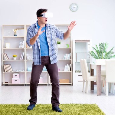 Evde sanal gerçeklik gözlüklü bir adam oynuyor.