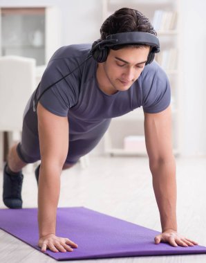 Adam evde spor yapıyor ve müzik dinliyor.
