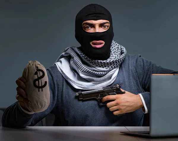 Terroristische inbreker met pistool werkend op computer — Stockfoto