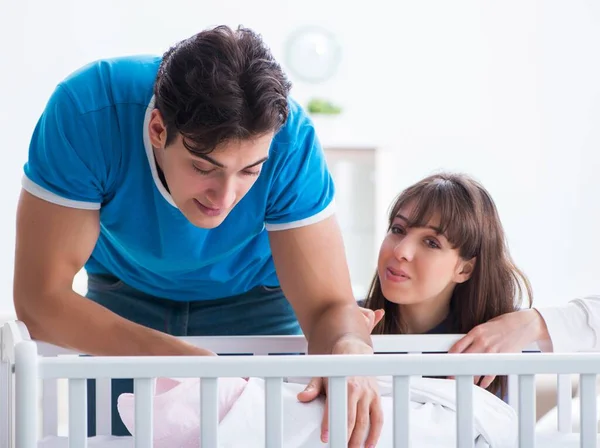 Happy young family at baby bed cot — Stock Photo, Image