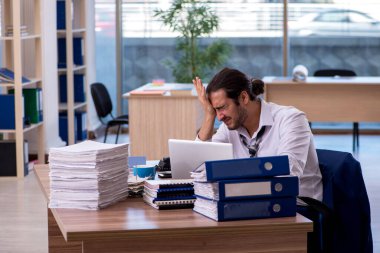 Ofisteki aşırı işten memnun olmayan genç bir erkek işçi.