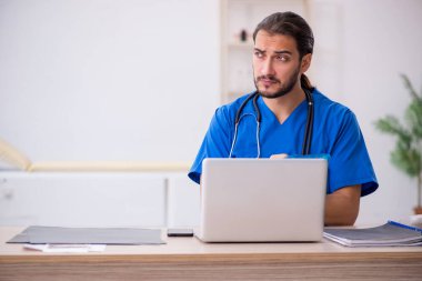 Klinikte çalışan genç erkek doktor.