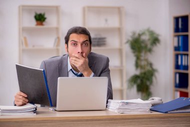 Ofisteki aşırı işten memnun olmayan genç bir erkek işçi.