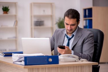 Ofisteki aşırı işten memnun olmayan genç bir erkek işçi.