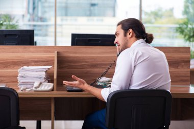 Genç bir erkek işçi ve ofiste çok fazla iş var.