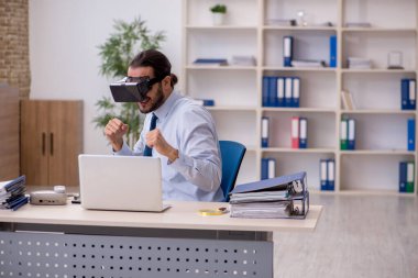 İş yerinde sanal gözlük takan genç bir erkek çalışan.