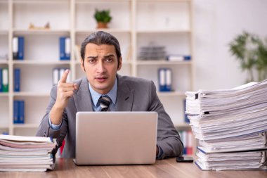 Ofisteki aşırı işten memnun olmayan genç bir erkek işçi.