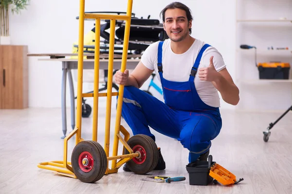 Молодой ремонтник ремонтирует тележку в помещении — стоковое фото