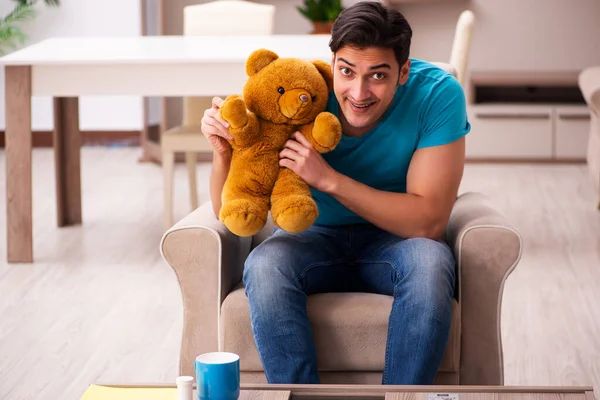 Jovem sentado com urso brinquedo em casa — Fotografia de Stock