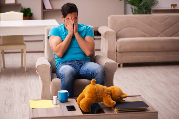 Молодой человек сидит дома с медвежьей игрушкой — стоковое фото