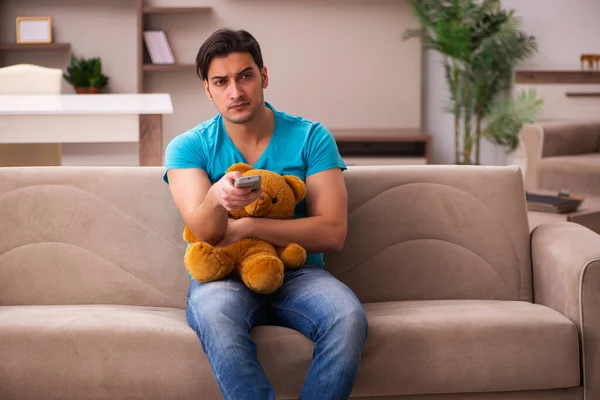 Jovem sentado com urso brinquedo em casa — Fotografia de Stock