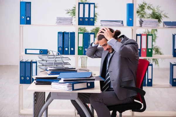 Jonge mannelijke werknemer ongelukkig met overmatig werk in het kantoor — Stockfoto