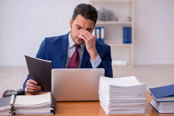 Ung affärsman och för mycket arbete på kontoret — Stockfoto