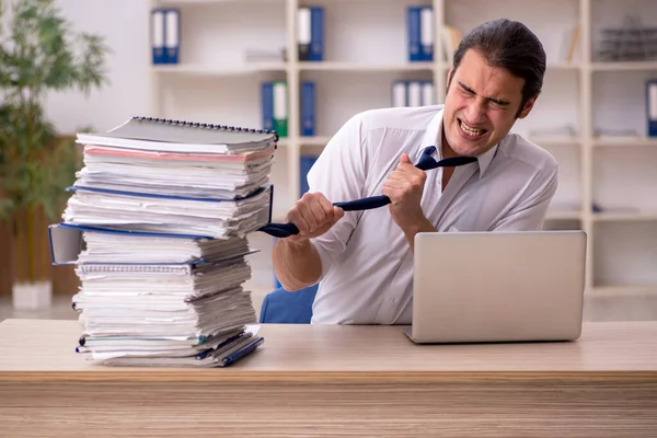 Joven empleado masculino y mucho trabajo en la oficina — Foto de Stock