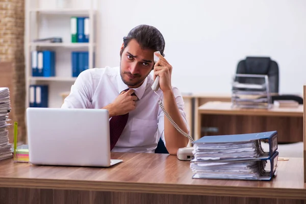 Jonge mannelijke werknemer ongelukkig met overmatig werk in het kantoor — Stockfoto