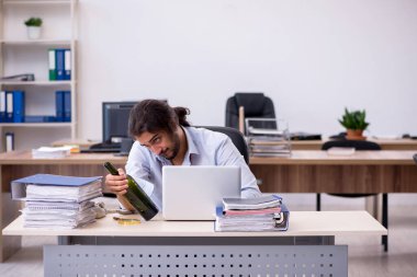 Genç erkek çalışan ofiste alkol içiyor.