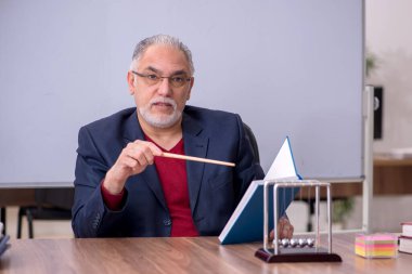 Sınıfta oturan eski bir fizikçi öğretmen.