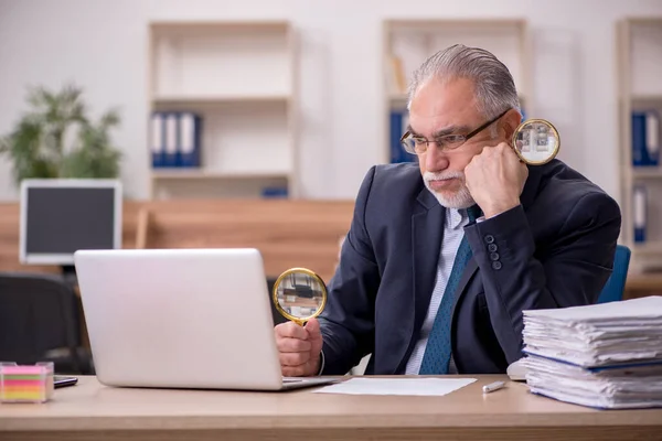 Velho empregado auditor segurando loupe no local de trabalho — Fotografia de Stock