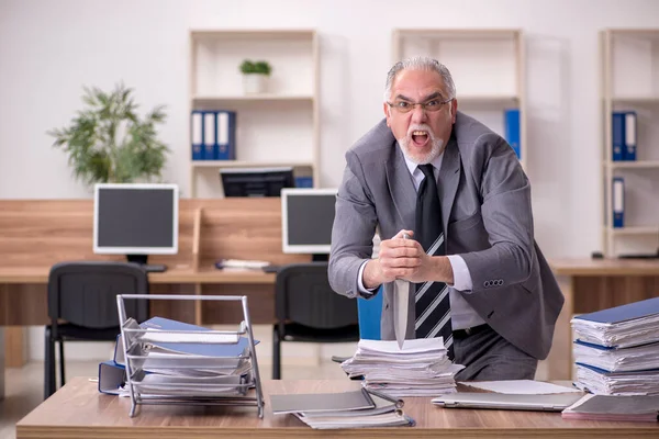 Old male employee unhappy with excessive work in the office — Stock Photo, Image