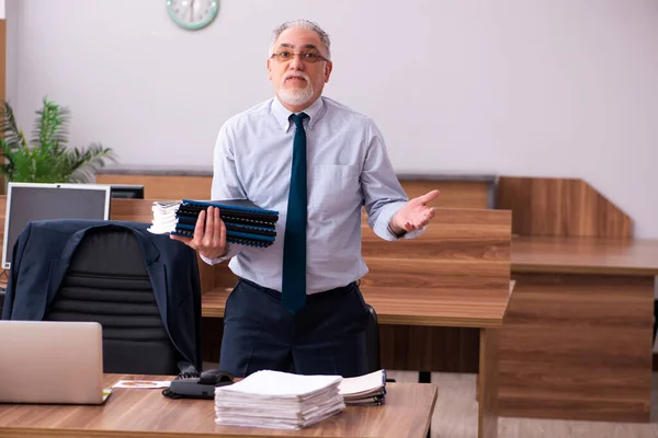 Velho empregado masculino e muito trabalho no escritório — Fotografia de Stock